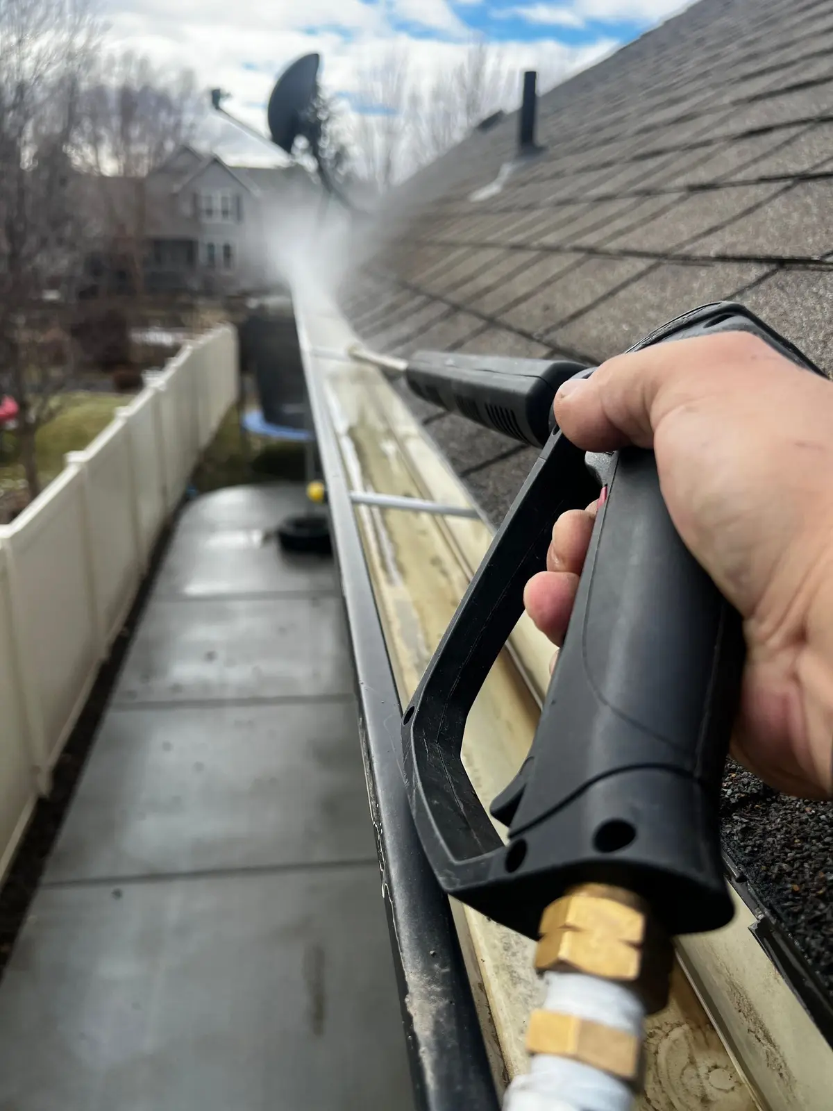 Flushing out a gutter along an asphalt shingle roof